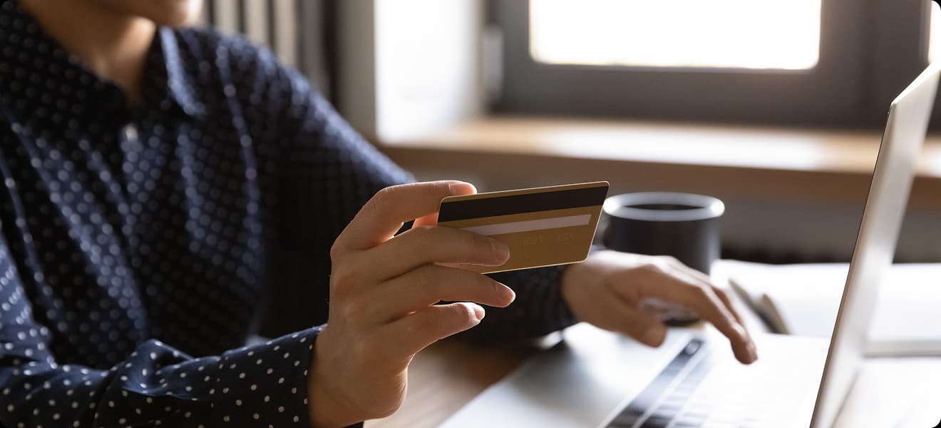 Vrouw betaalt online met een creditcard achter haar laptop